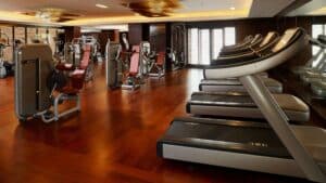 Empty gym at Sheraton Cairo Hotel with treadmills, weight machines, and wooden flooring.