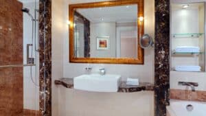 Luxurious bathroom at Sheraton Cairo with a marble sink, large mirror, and glass shelves.