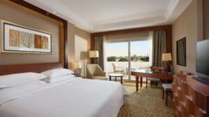 Sheraton Cairo Hotel room with king bed, desk, TV, and balcony seating.