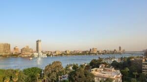 Cityscape with a river, Sheraton Cairo, buildings, and greenery under a clear blue sky.