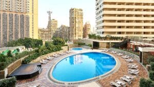 Sheraton Cairo Hotel & Casino boasts an oval pool with lounge chairs in an urban setting.