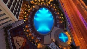 Aerial view of Sheraton Cairo Hotels illuminated pool with lounge chairs at night.