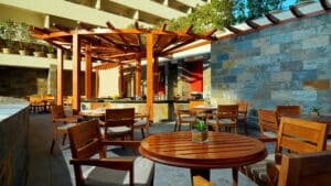 Outdoor patio at Sheraton Cairo Hotel with wooden tables, stone walls, and a wooden pergola.