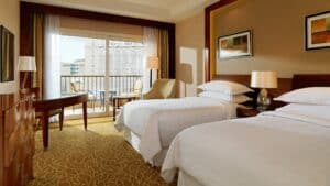 Sheraton Cairo room: two beds, desk, chair, lamps, and a balcony with a city view.