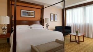 Sheraton Cairo room: four-poster bed, sofa, and large window with curtains.
