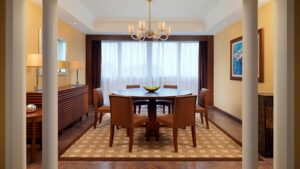 A dining room with a round table, six chairs, and a chandelier reminiscent of the Sheraton Cairo Hotel.