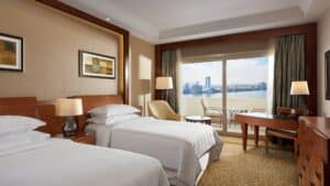 Sheraton Cairo room: two beds, desk, chair, large window with city view.