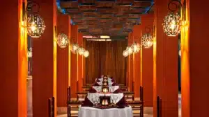 Sheraton-inspired interior with warm lighting, orange pillars, and tables set for dining.