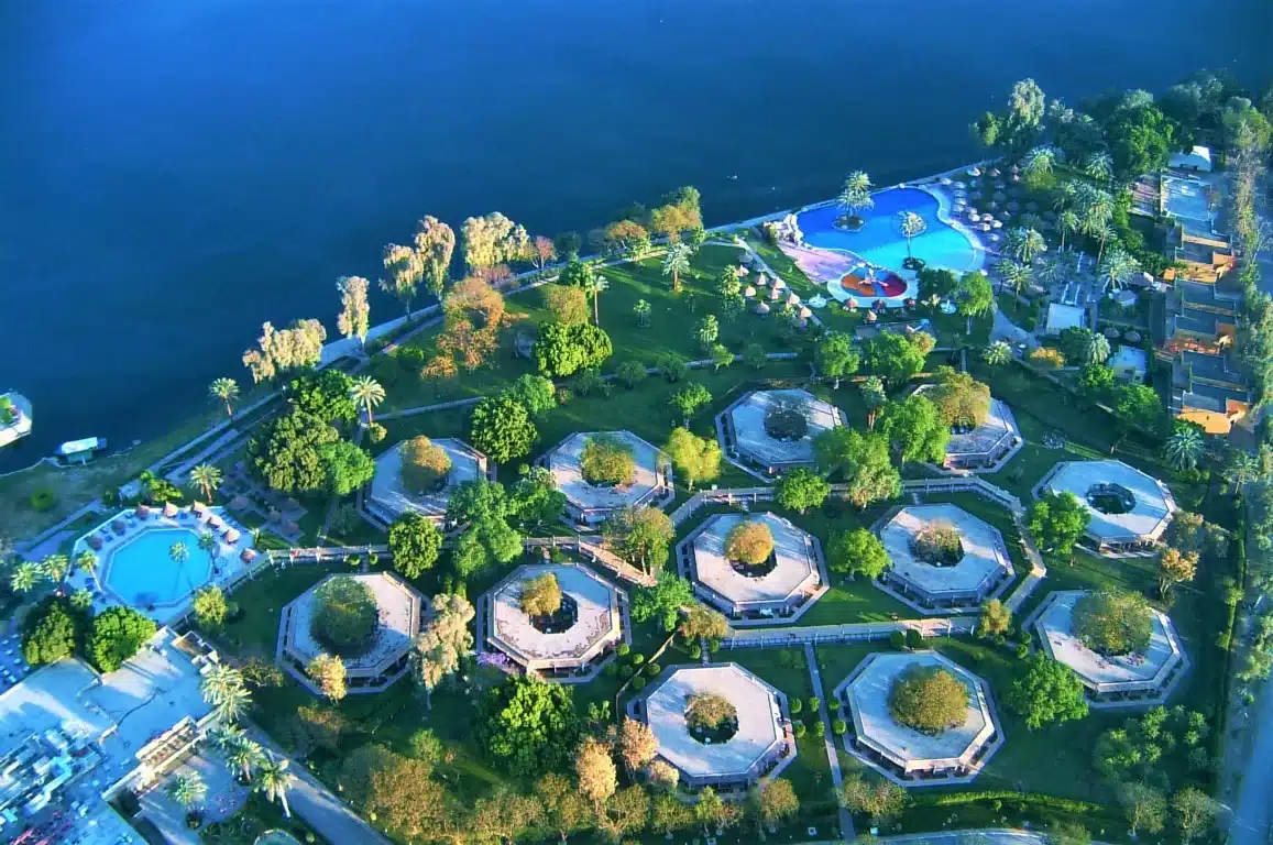 Aerial view of hexagonal buildings near a Jolie Ville Kings Island pool by the water.