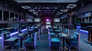Modern nightclub at Sheraton Cairo Hotel, empty with tables, chairs, and neon lights.