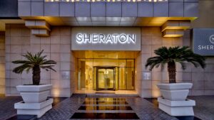 Sheraton Cairo Hotel entrance with revolving door and two large potted plants.