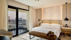 Sheraton Cairo room with a bed, balcony access, and city view through glass doors.