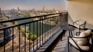 Chairs on a balcony with views of the river and Sheraton Cairo Hotel & Casino in the distance.
