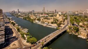 Aerial view of a cityscape with Sheraton Cairo Hotel & Casino, river, bridge, and high-rises.
