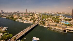Aerial view of a city with a river, bridge, and Sheraton Cairo Hotel & Casino in sight.