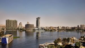 Panoramic view of a city skyline, with Sheraton Cairo Hotel & Casino by the river under a clear sky.