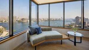 Room at Sheraton Cairo with a chaise lounge, city views, and river through large windows.