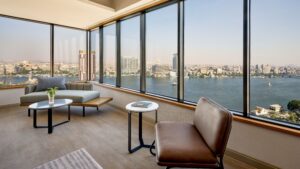 Modern room at Sheraton Cairo with large windows overlooking a wide river and cityscape.