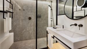 Modern bathroom at Sheraton Cairo with a glass shower, round mirror, and sleek black fixtures.