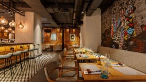 Modern restaurant at Sheraton Cairo with wooden tables, bar stools, and a mural on brick wall.