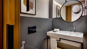 Modern bathroom at Sheraton with round mirror, art, and a sleek sink with towel beneath.
