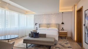 Modern room at Sheraton Cairo Hotel with double bed, bedside tables, and seating by large windows.
