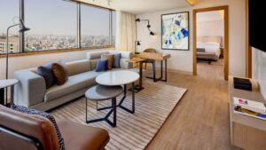 Modern Sheraton Cairo room with seating, desk, and cityscape view through large windows.