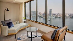 Modern room at Sheraton Cairo with a chaise lounge and river view through large windows.