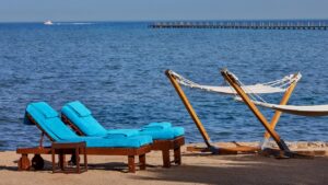 Two blue lounge chairs and two hammocks by the sea at Sheraton Miramar Resort.