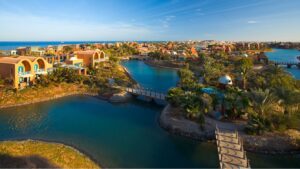 Aerial view of Sheraton Miramar Resort with lagoons, bridges, and palms under a clear blue sky.