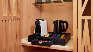 Coffee machine and kettle on a tray with pods in a Sheraton Miramar Resort cabinet.