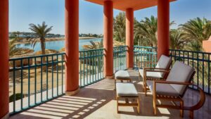 The Sheraton Miramar Resort balcony offers cushioned chairs overlooking palms and water.