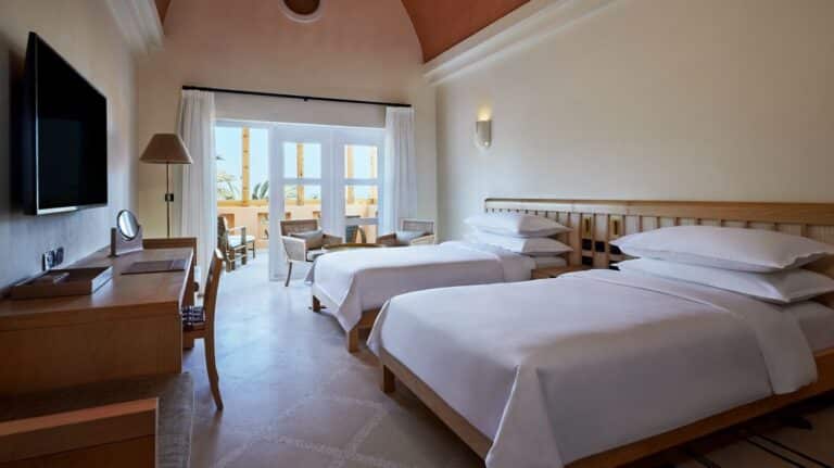Sheraton Miramar Resort room: two beds, desk, TV, and balcony with outdoor seating.