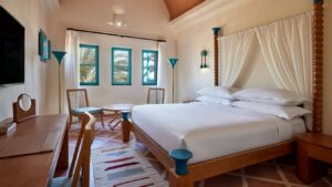 Room at Sheraton Miramar Resort: large bed, chairs, desk, and views of palm trees.