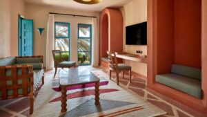 Modern living room with colorful rug, seating, TV, and Sheraton Miramar Resort palm tree views.