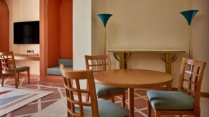Room with wooden chairs, round table, wall-mounted TV, and decorative lamps at Sheraton.
