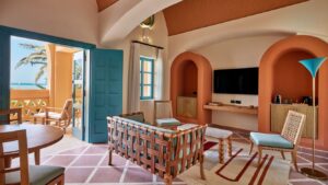Stylish room interior with TV, woven furniture, and an ocean-view balcony at Sheraton Miramar Resort.