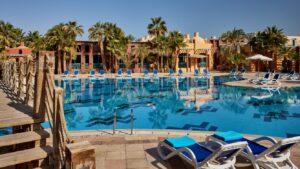 Sheraton Miramar Resorts pool, with palm trees and blue lounge chairs under a clear sky.