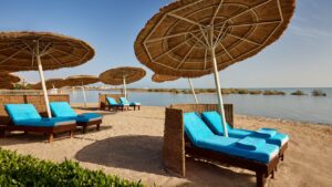 Beach at Sheraton Miramar Resort: lounge chairs, blue cushions, umbrellas by a calm sea.