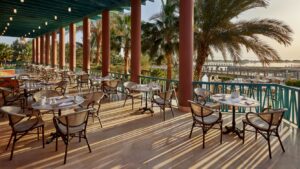 Sheraton Miramars terrace offers tables, chairs, and views of palm trees and water.