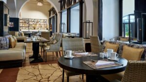 Sheraton Miramars cozy restaurant has set tables, cushioned chairs, and decorative shelves.