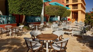 Sheraton Miramar patio with tables, lush greenery, and a building with orange walls and teal accents.
