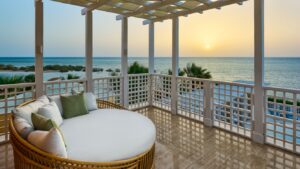 Sunset view from a Sheraton Miramar Resort balcony with a daybed overlooking the ocean.