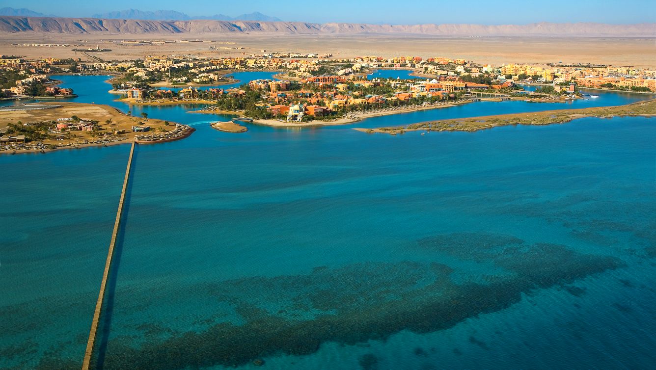 Aerial view of Sheraton Miramar Resort with turquoise waters and distant mountains.