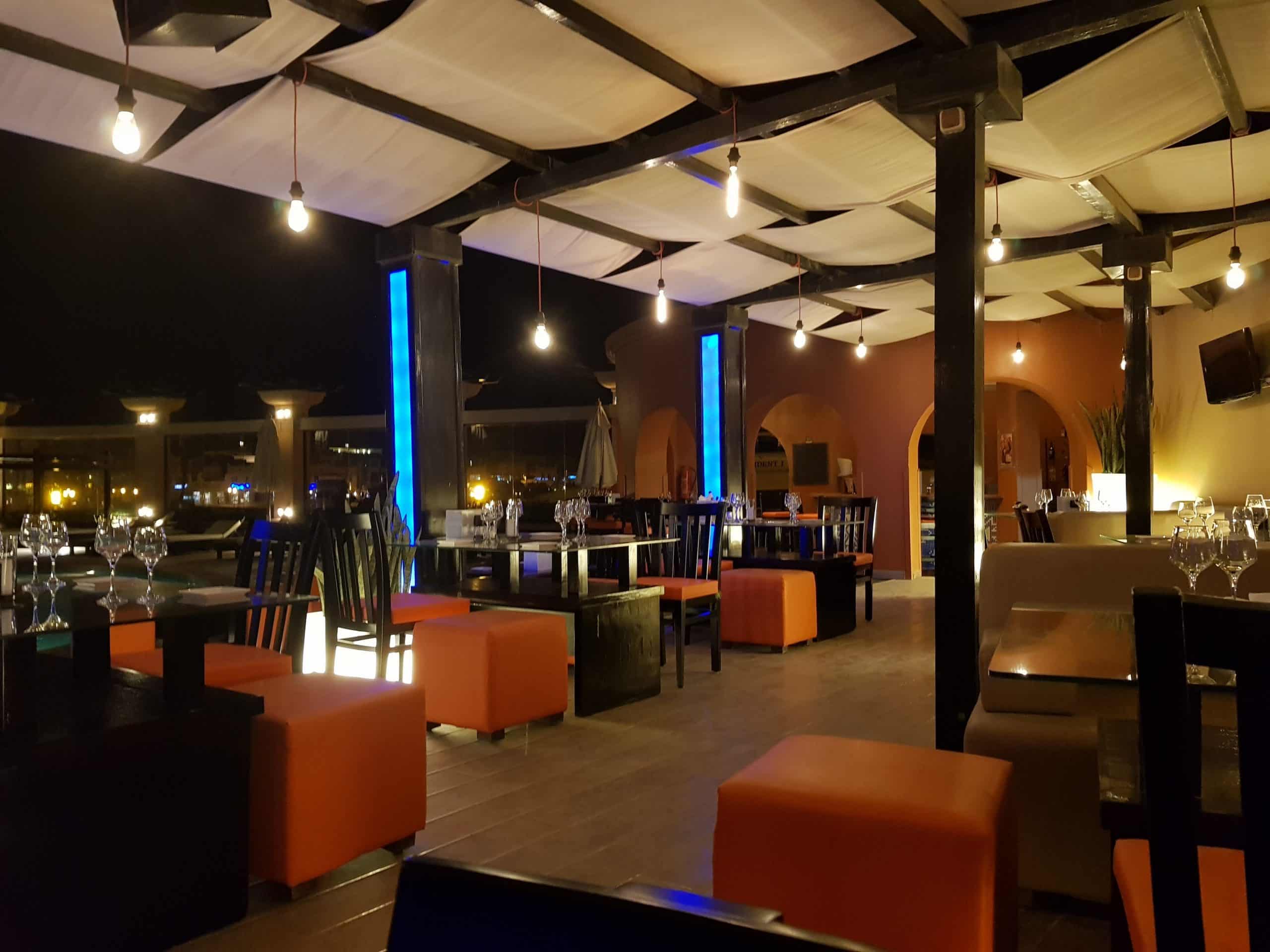 Three Corners Ocean View: An outdoor patio with tables, chairs, and ambient lighting at night.