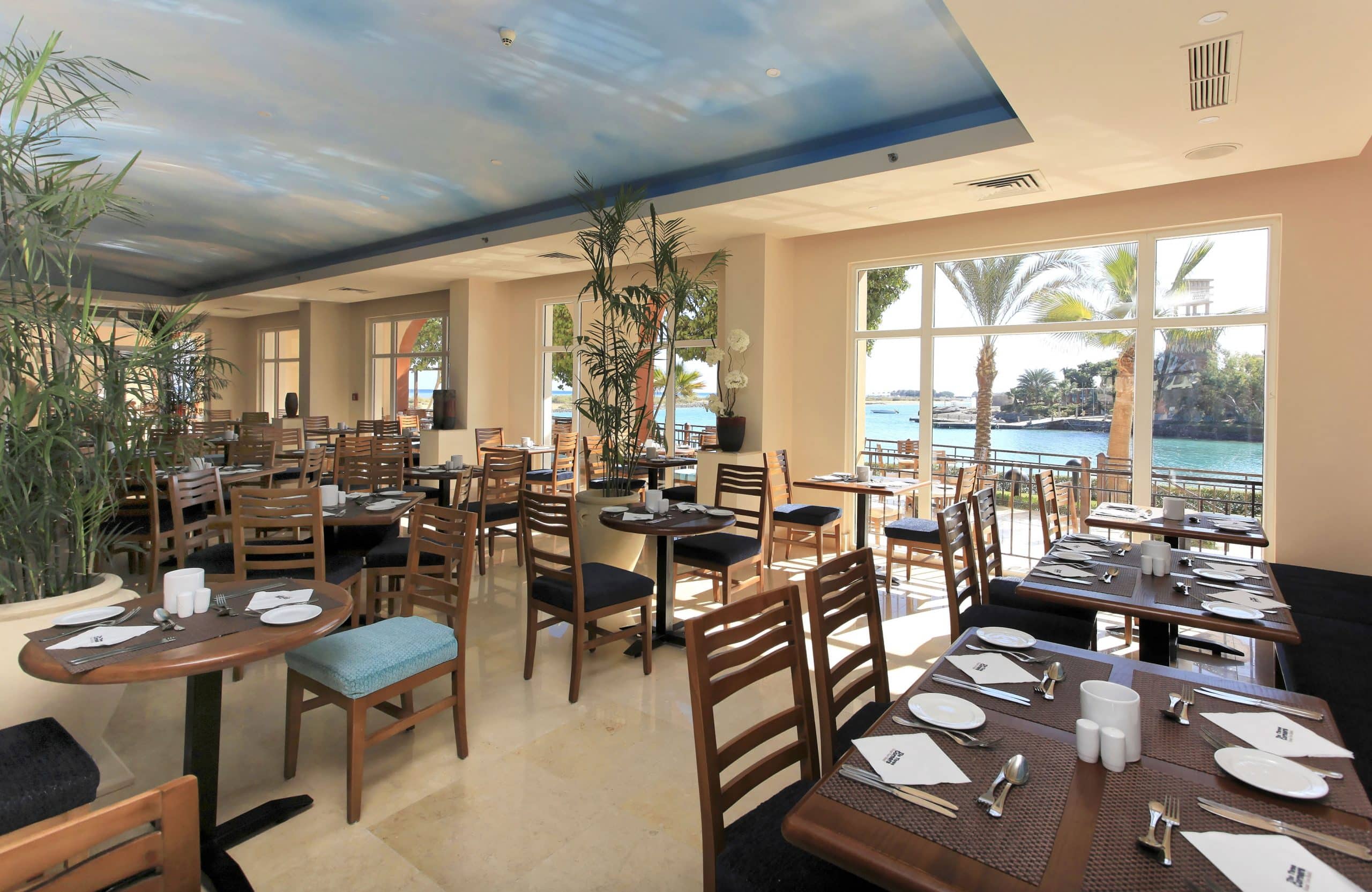 Sunny restaurant, set for dining at Three Corners Ocean View, overlooks a waterfront view.