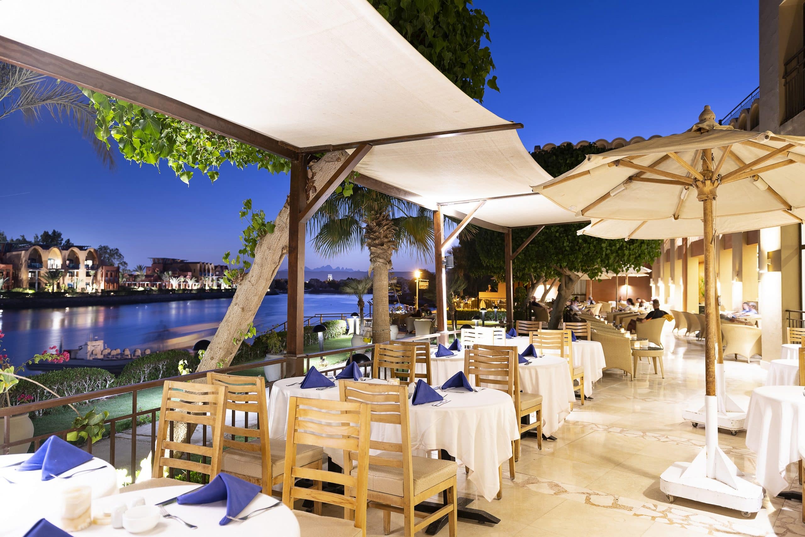 Riverside dinner at twilight under canopies, with a serene Three Corners Ocean View.