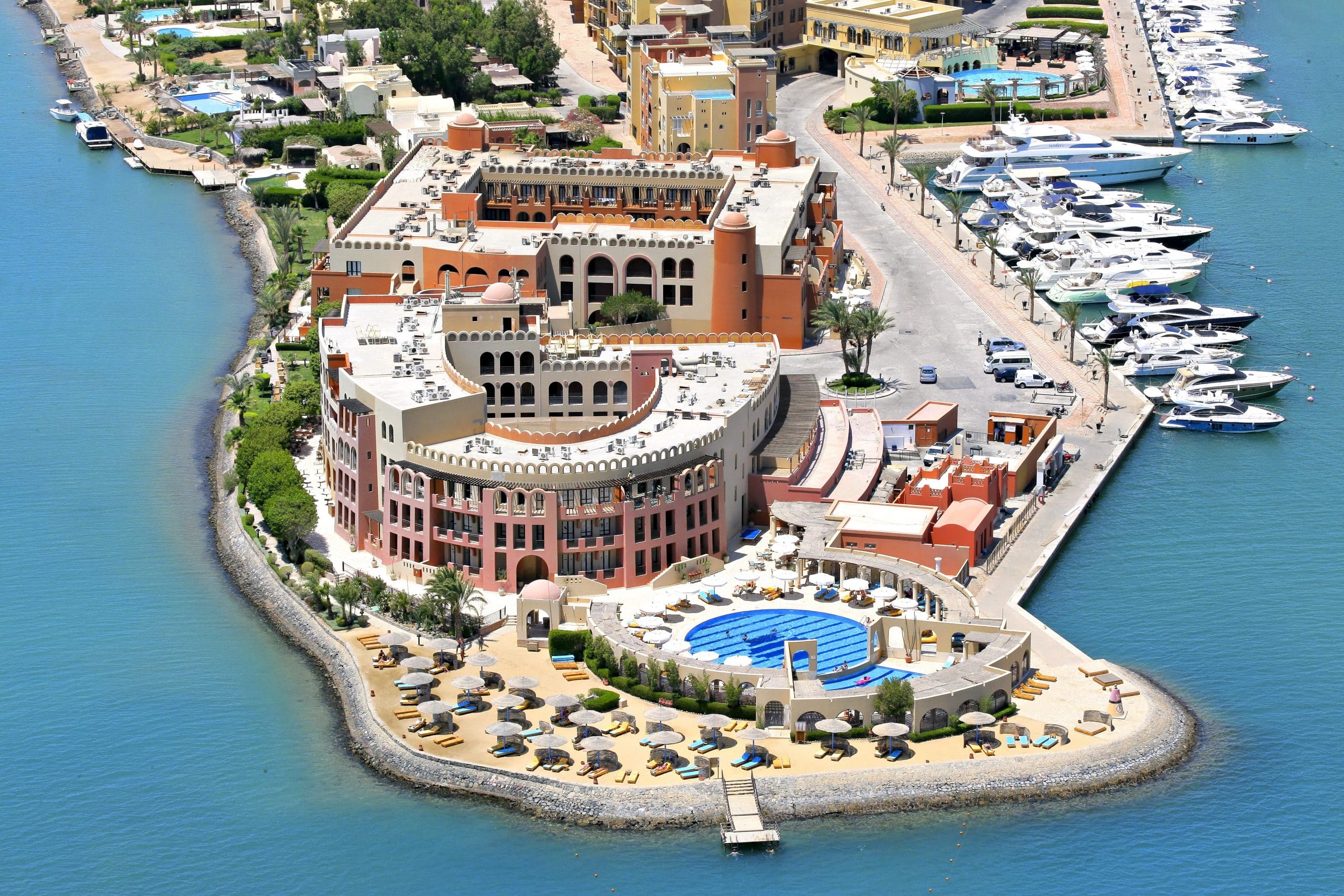 Aerial view of Three Corners Ocean View, a coastal resort with pools and moored yachts.