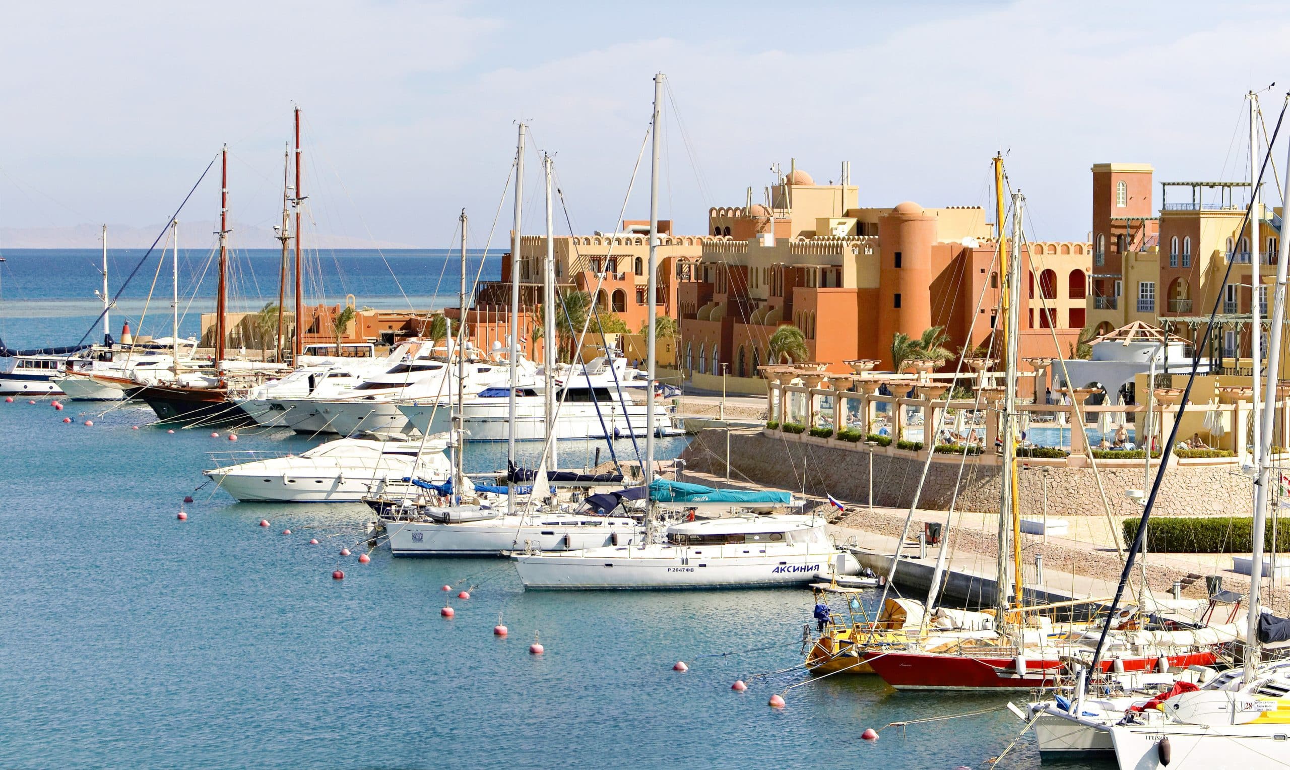 Boats docked in a marina with Three Corners Ocean Views colorful buildings behind.