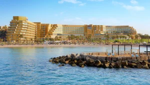 Hilton Hurghada: Beachfront hotel with palm trees and sun loungers by the sea.